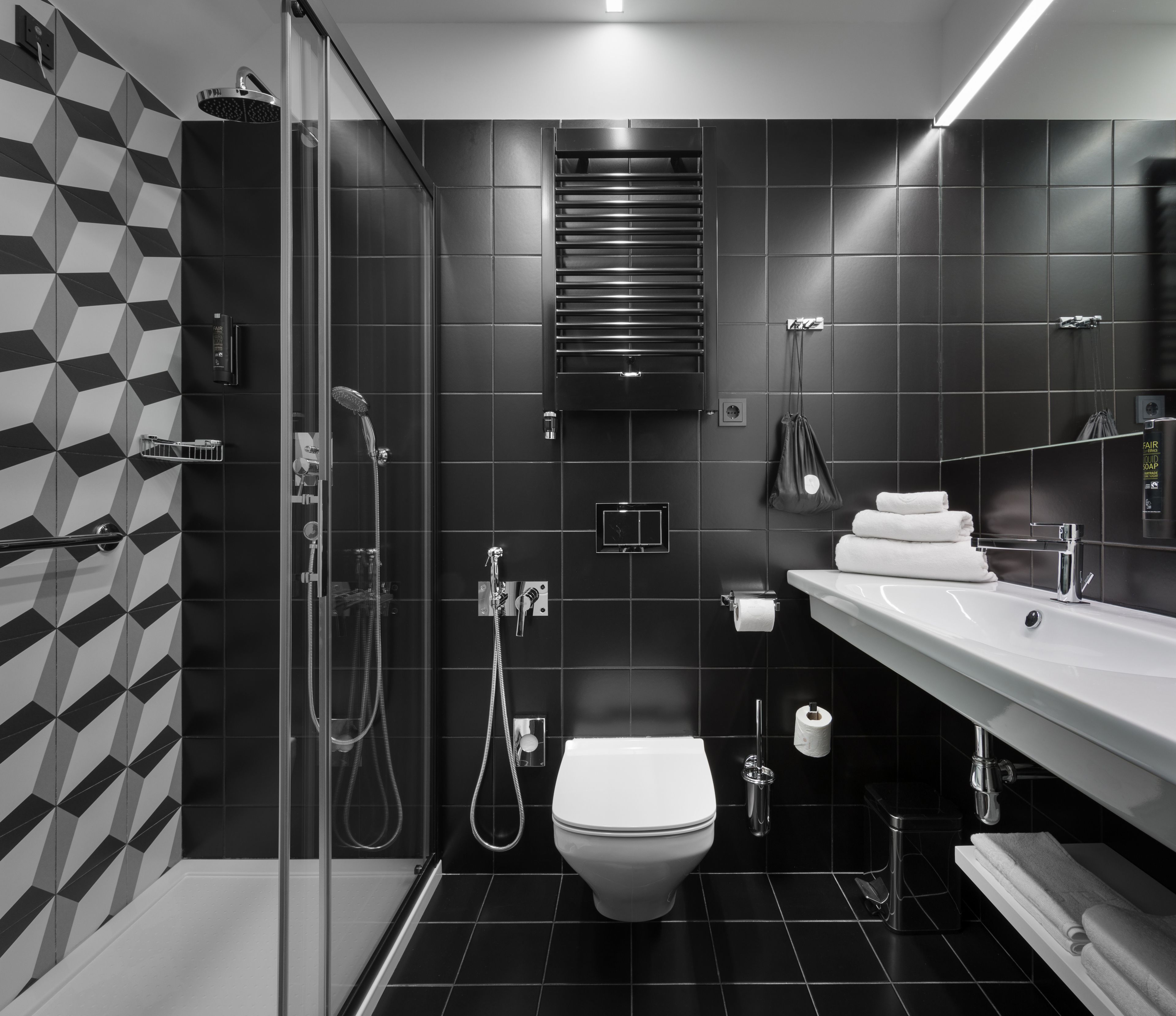 A modern bathroom with a glass-enclosed shower, a white toilet, a sink with a mirror, and a towel rack.