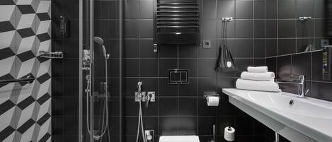 Un baño moderno con ducha envuelta en vidrio, inodoro blanco, lavabo con espejo y toallero.