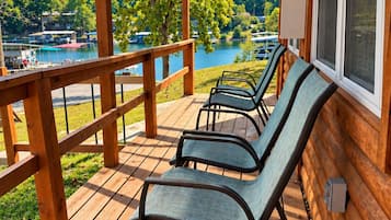A wooden deck with a covered area, overlooking a body of water and boats.