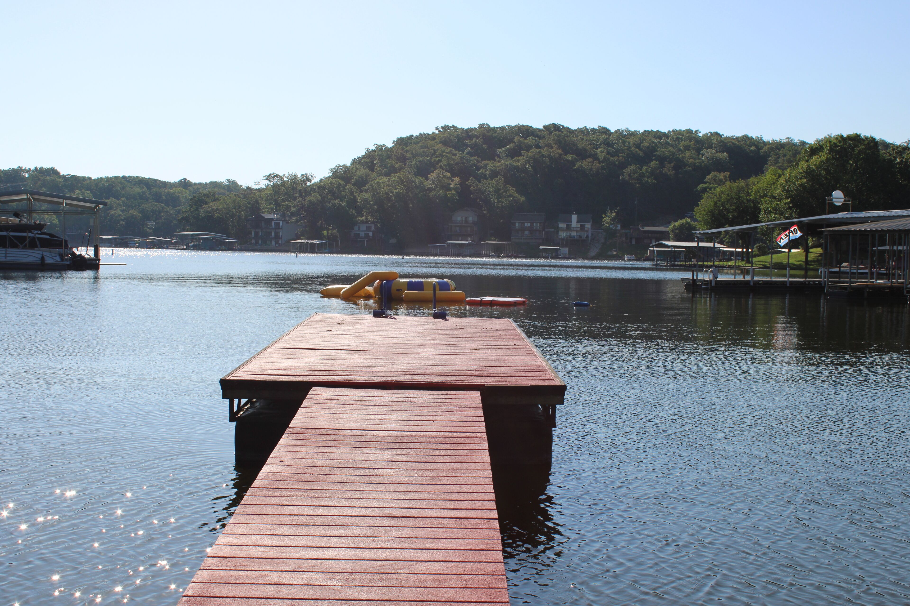Un muelle de madera se extiende sobre aguas tranquilas bajo un cielo despejado.