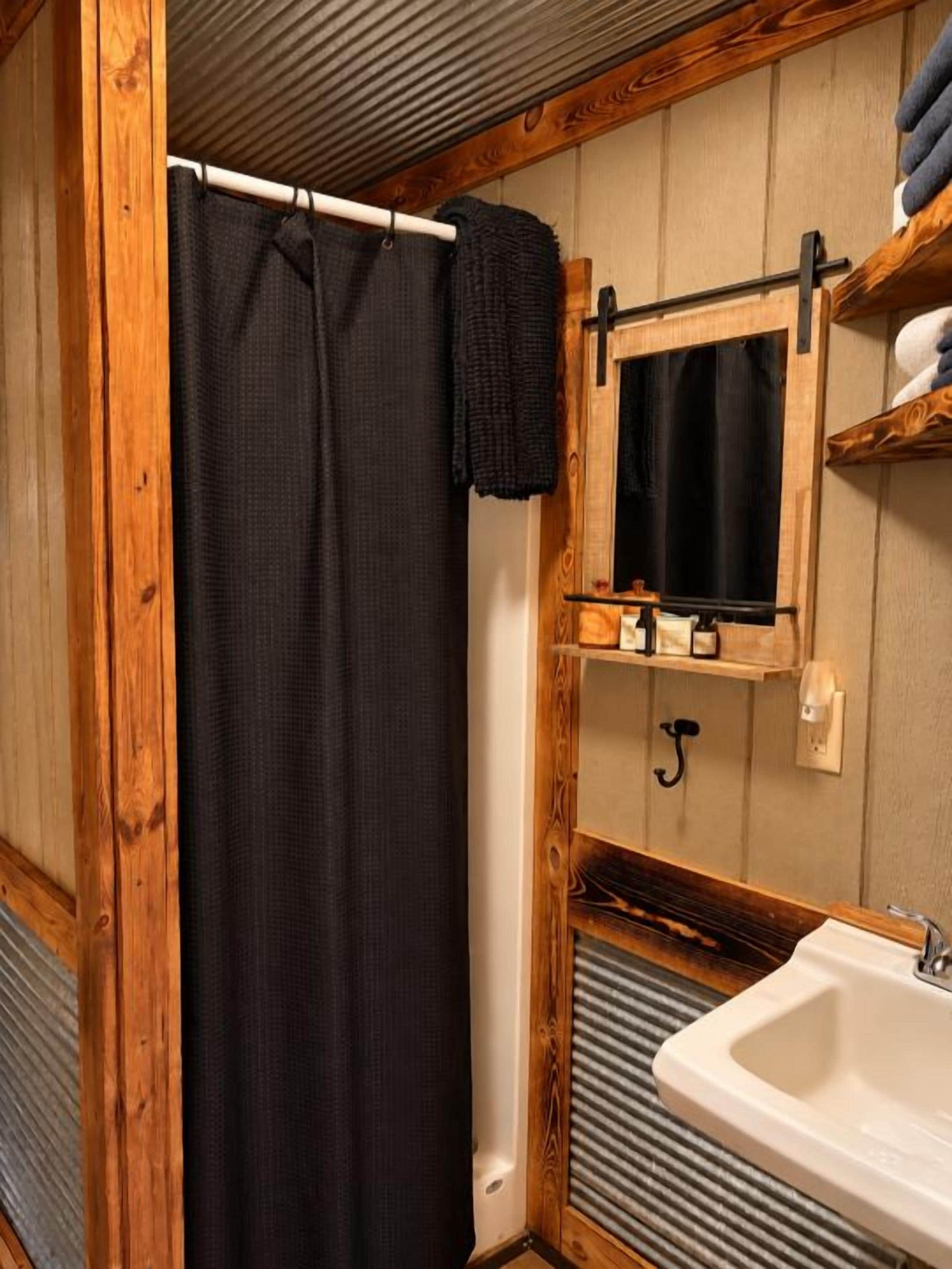 A bathroom with a shower curtain, a sink, and a mirror.
