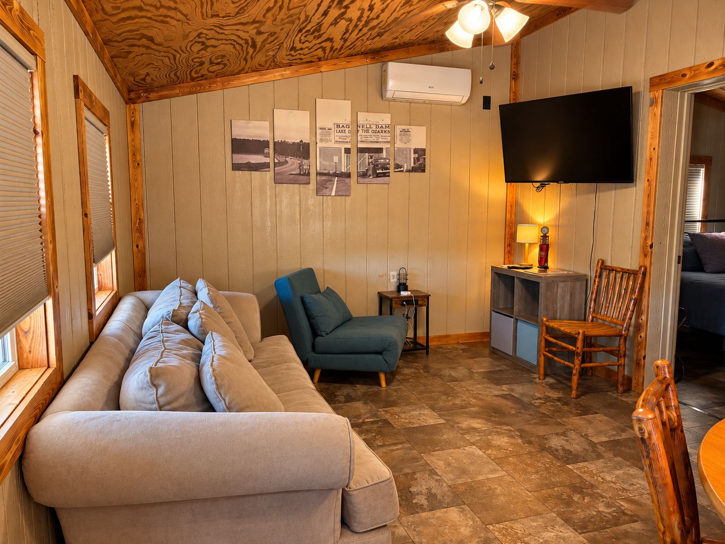 A cozy living room with a sofa, a chair, a TV, and a small table with a lamp.