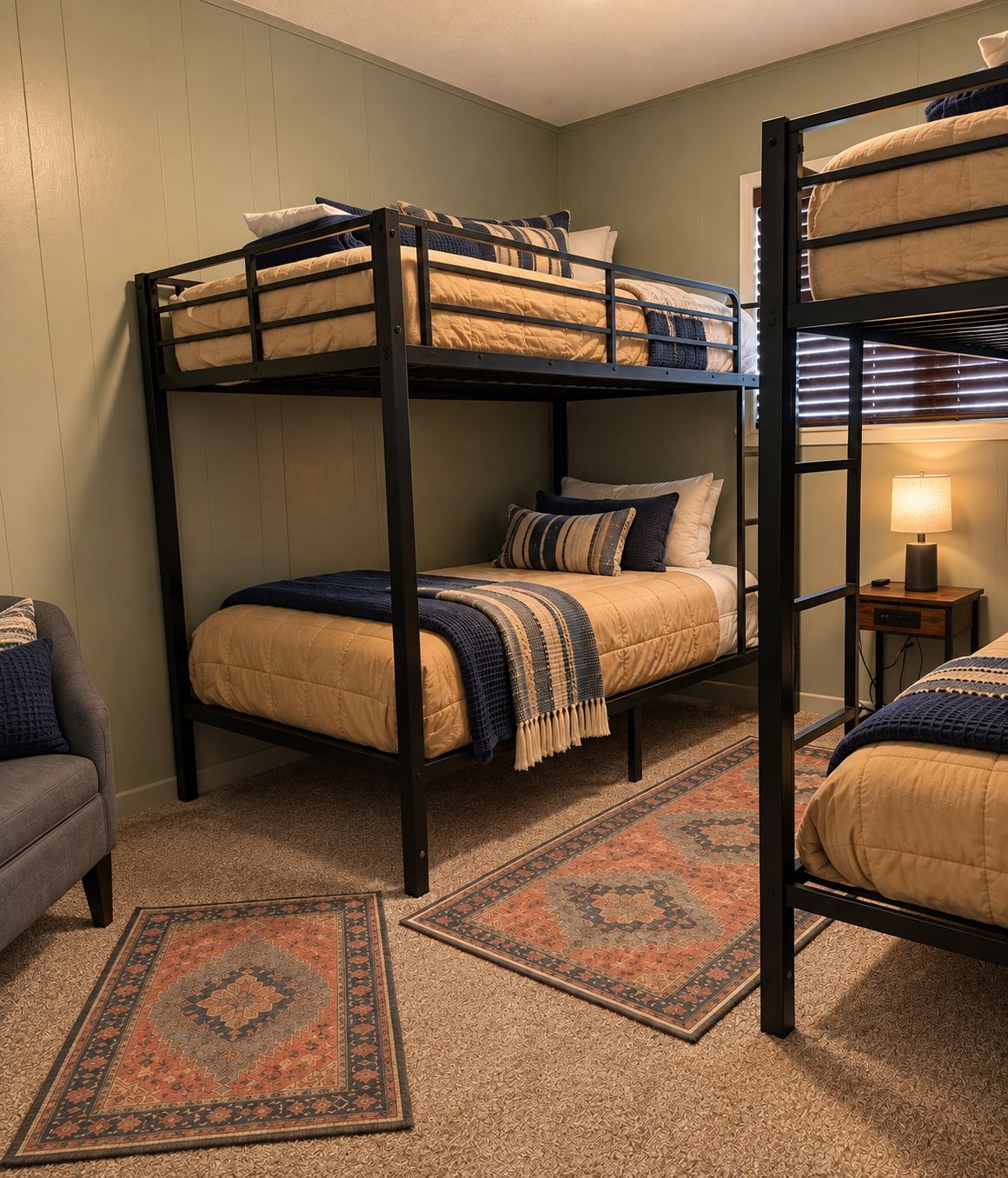 A bunk bed room with a patterned rug and a small table with a lamp.