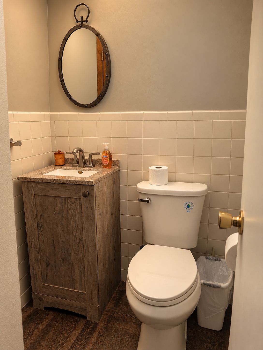 A bathroom with a wooden vanity, a toilet, and a wall-mounted mirror.