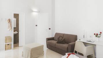 Un salon moderne et minimaliste, avec un canapé marron, un bureau blanc et une petite table.