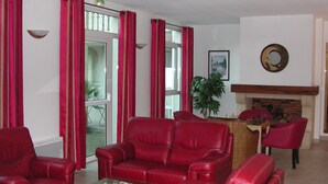 Un salon avec des canapés en cuir rouge, une table basse en verre et une cheminée.