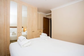 Relax in a spacious room with a large bed, a wooden wardrobe, and a bedside table.