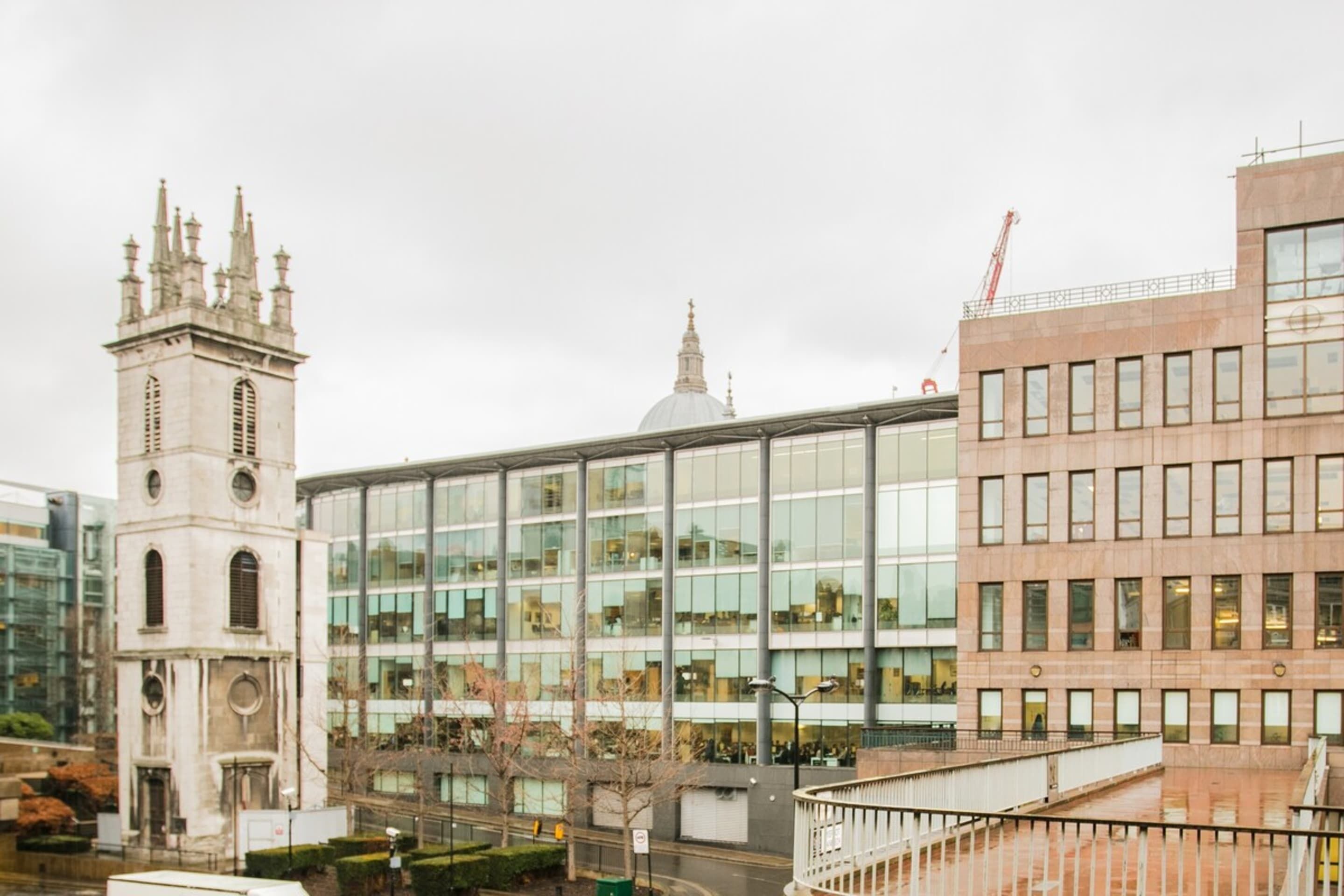 A modern building with a glass facade and a historic tower with a dome.