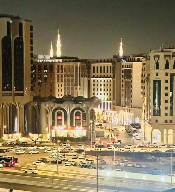 A cityscape at night with illuminated buildings, a busy street, and a prominent mosque with two minarets. - Sidra Alia AL-DAHABI hotel - فندق السدرة العالية الذهبي (Madinah)