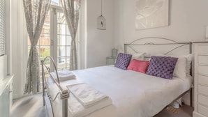 Una camera da letto con un letto, tende, un comodino, una lampada a parete e una finestra.