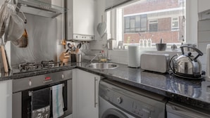 Una cucina moderna con elettrodomestici in acciaio inossidabile, una finestra vista un edificio in mattoni e un tostapane sul bancone.