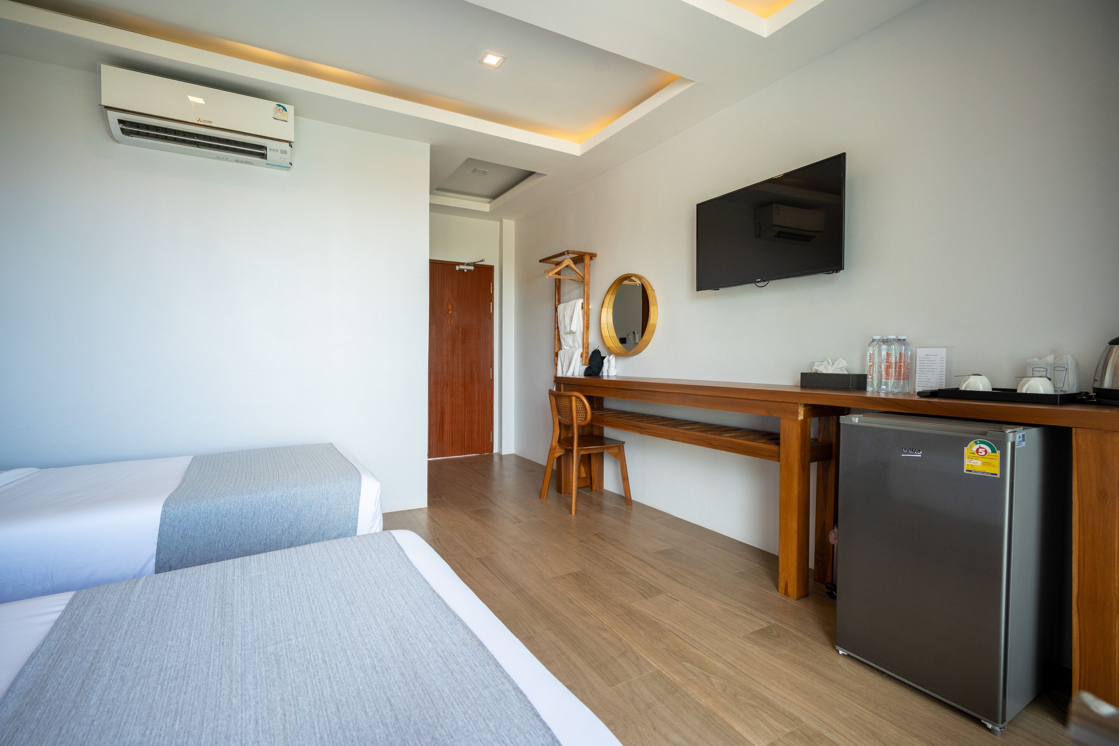 Habitación de hotel con dos camas, un escritorio, un refrigerador, un televisor y aire acondicionado.