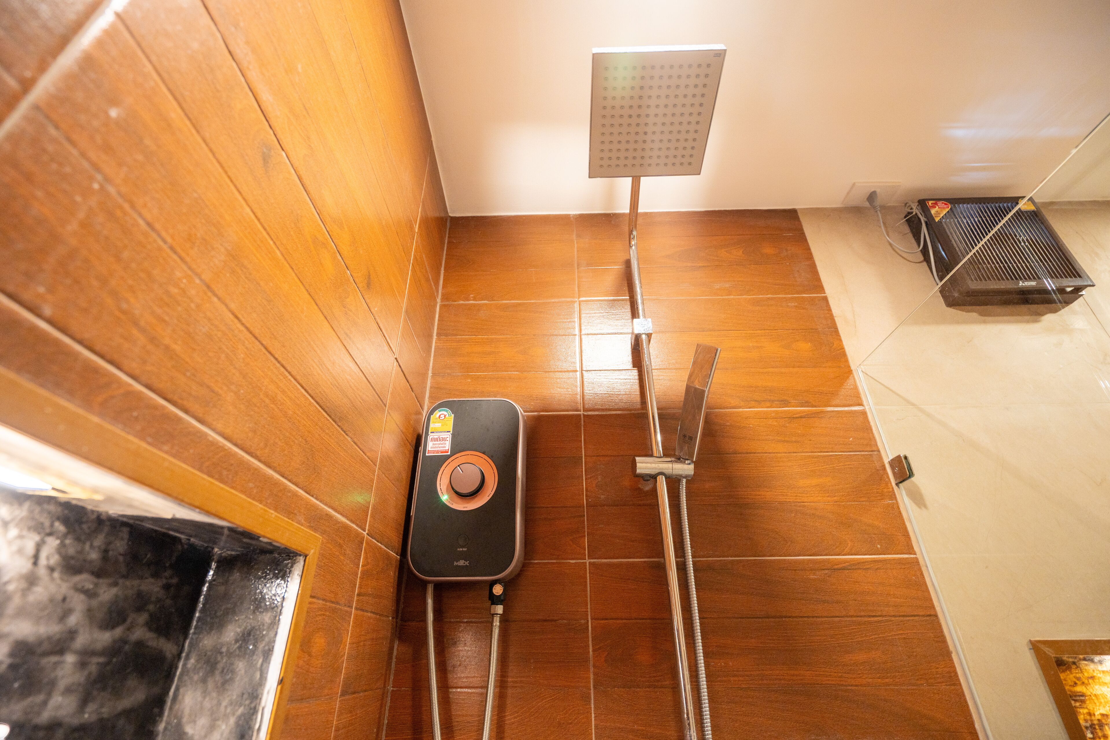 A shower area with a handheld showerhead, a handheld shower attachment, and a water heater.