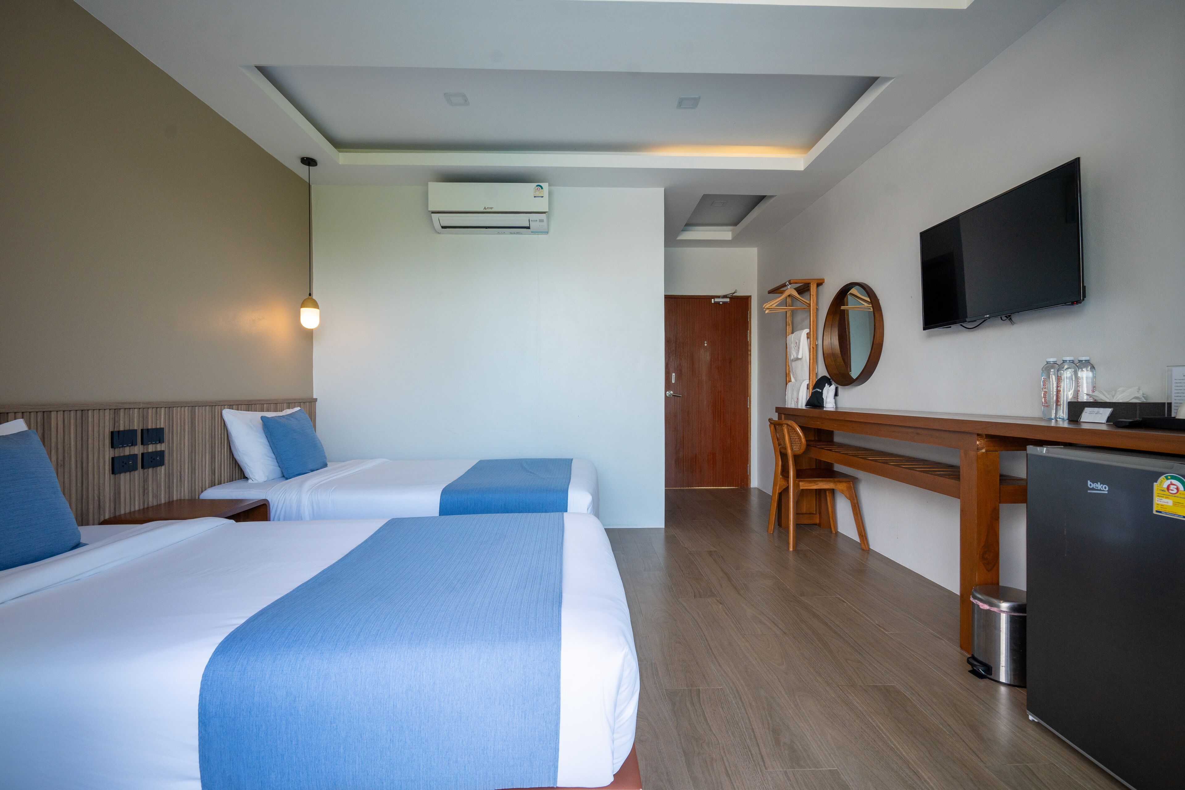 Een hotelkamer met twee bedden, een bureau, een televisie en een minibar.
