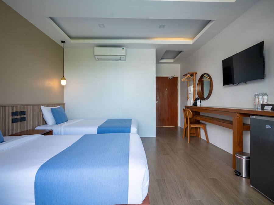 Een hotelkamer met twee bedden, een bureau, een televisie en een minibar.