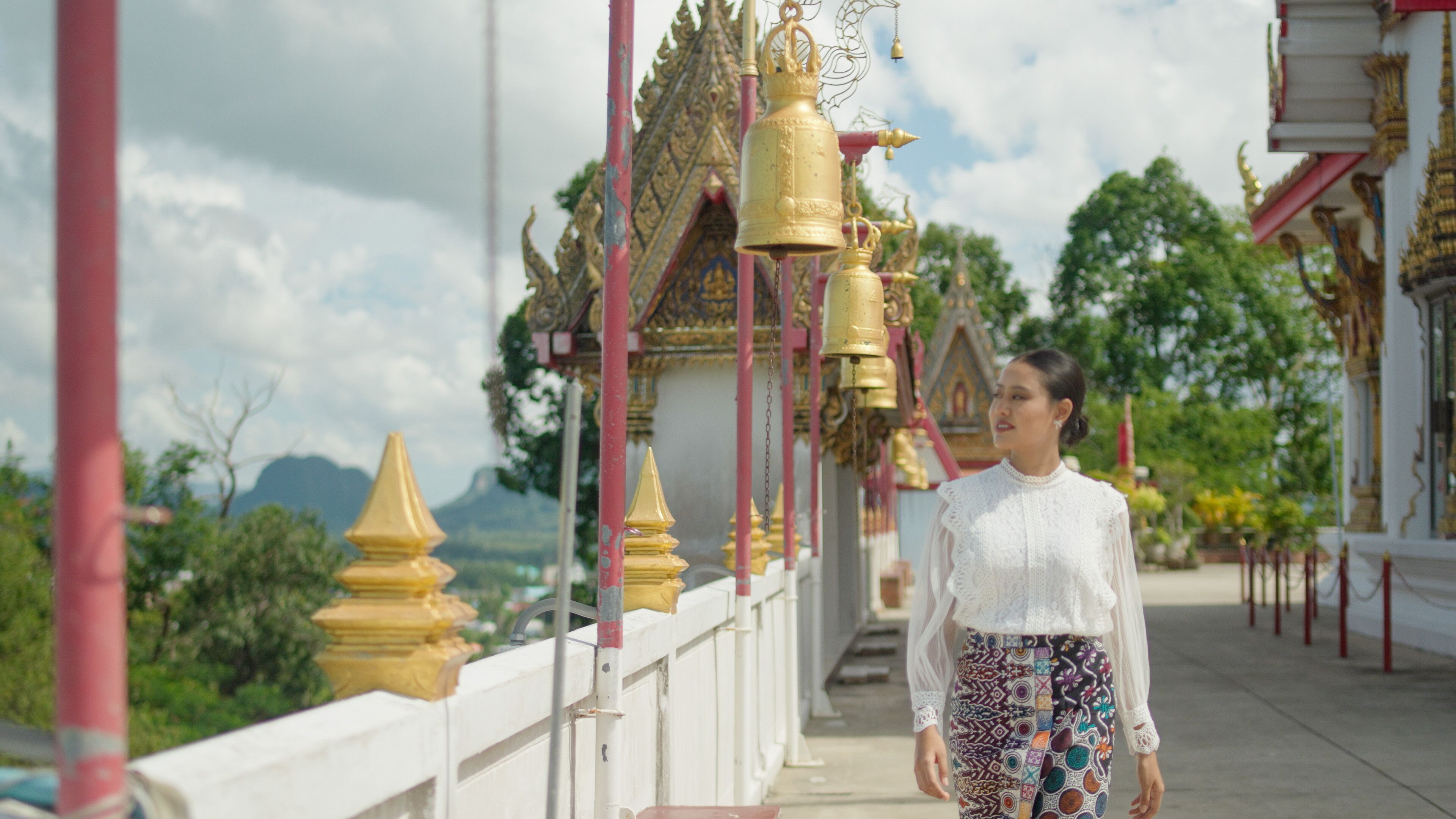 A person walking on a bridge with traditional architecture and golden decorations.