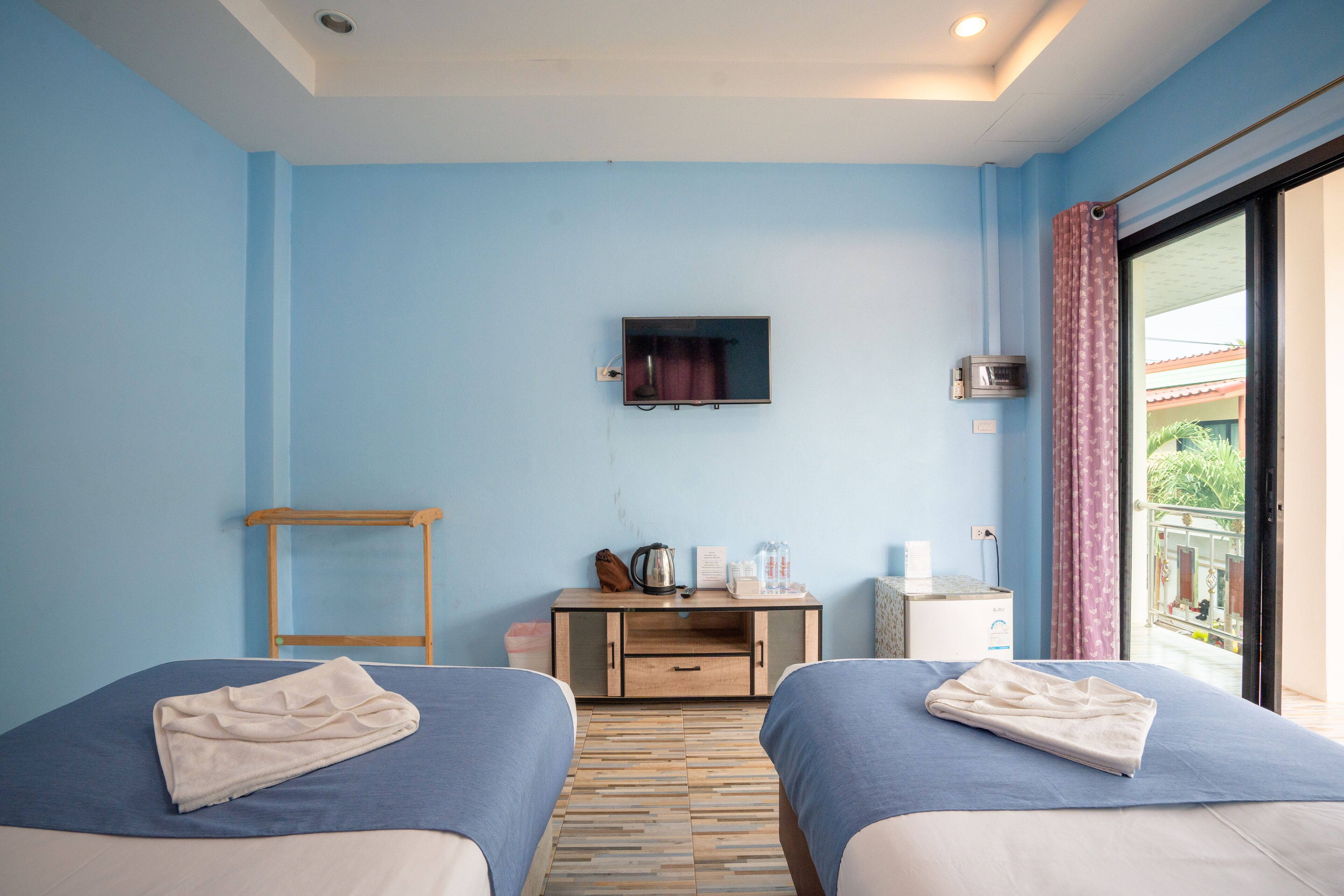 A hotel room with two beds, a TV, a small desk, and a window with a view.