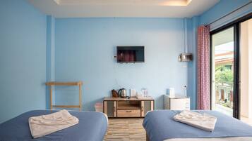 A hotel room with two beds, a TV, a small desk, and a window with a view.