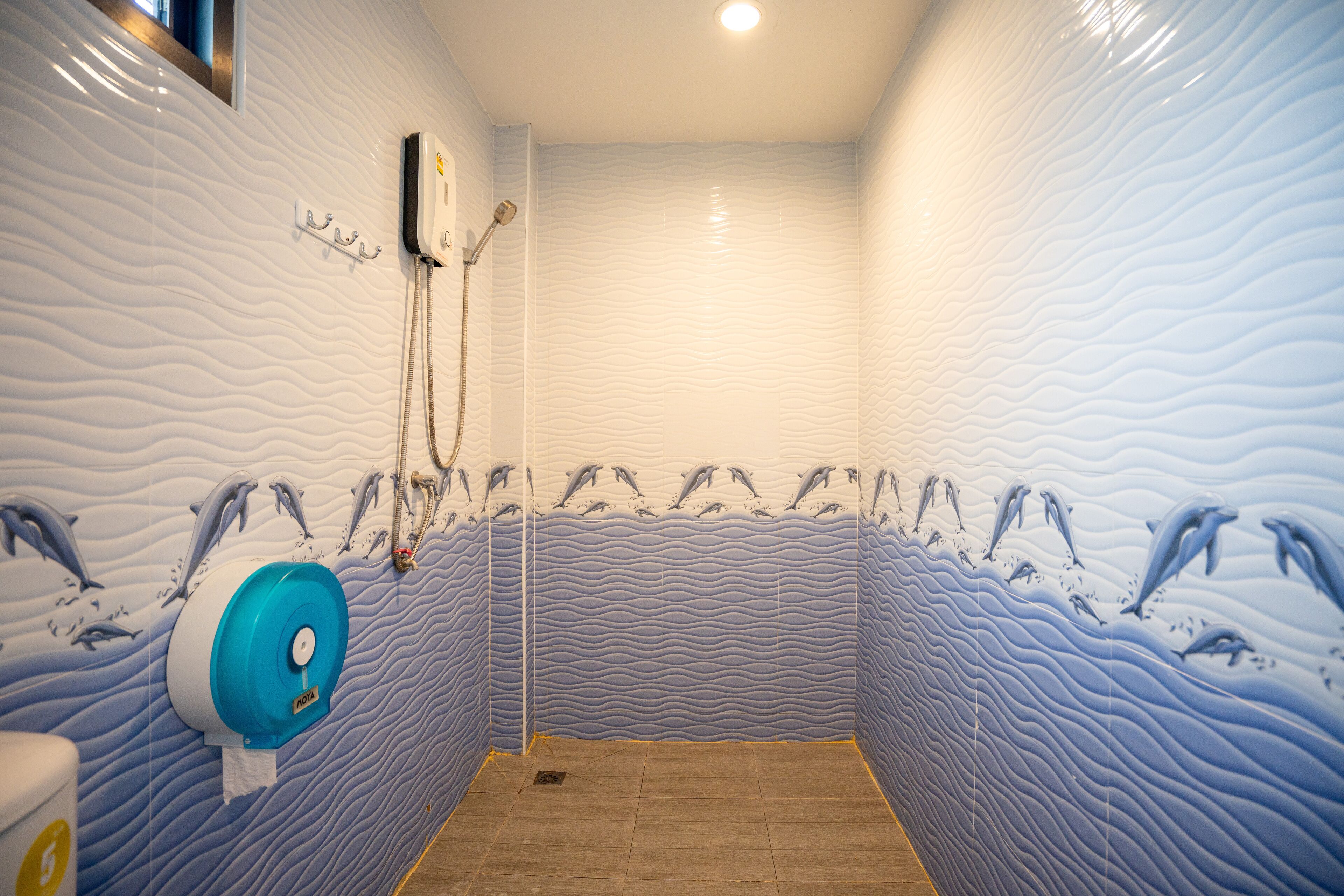 Un baño con un diseño de pared ondulado, un cabezal de ducha y un inodoro.