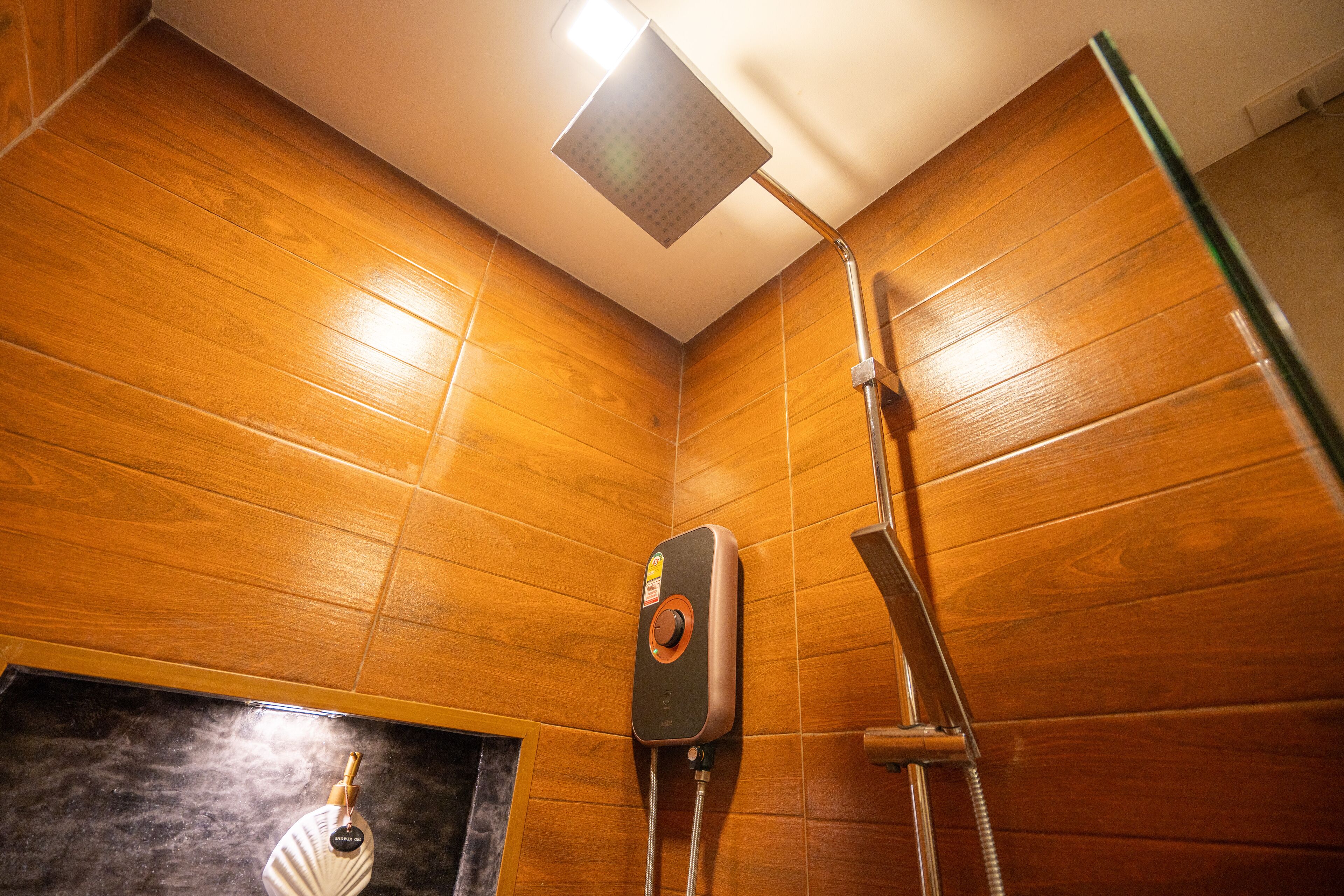 A wooden-paneled shower room with a handheld showerhead and a wall-mounted control panel.