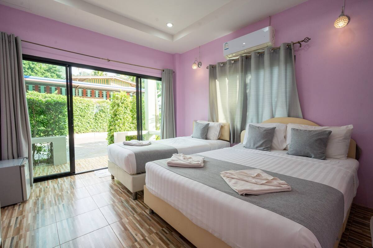 A hotel room with two beds, a sliding glass door to the outside, and an air conditioning unit on the wall.