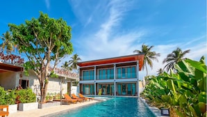 Un hôtel moderne doté d’une piscine, de palmiers et de chaises longues.