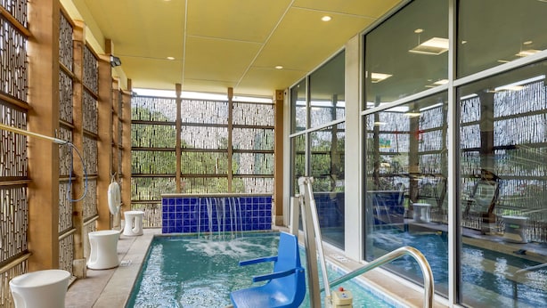 A pool area with a blue chair, a ladder, and a no swimming sign. - GLō Best Western Dallas South DeSoto (DeSoto)