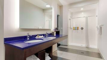 A modern bathroom with dual sinks, a large mirror, and a walk-in shower.