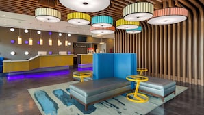 A modern lobby with a reception desk, seating area, and colorful pendant lights. - GLō Best Western Dallas South DeSoto (DeSoto)