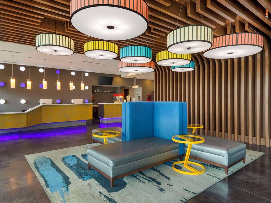 A modern lobby with a reception desk, seating area, and colorful pendant lights.