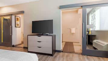 A hotel room with a bed, a TV on a dresser, a sliding door, and a bathroom visible through the door.
