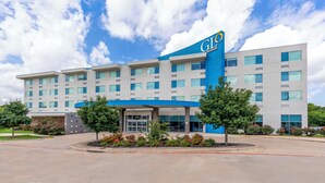 A hotel with a modern design, featuring a prominent blue and white color scheme, multiple floors, and a well-maintained exterior with landscaping. - GLō Best Western Dallas South DeSoto (DeSoto)