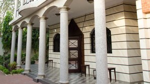 Un edificio con balcón cubierto, columnas y piso de baldosas.