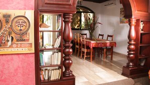 Un comedor con una mesa y sillas de madera, una estantería y un adorno en la pared.