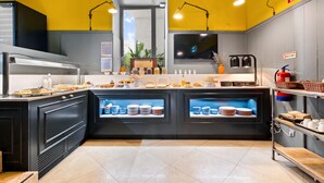 Una cocina con techo amarillo, armarios negros y una encimera mostrando diversos alimentos.