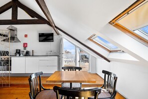 A modern kitchen with white cabinets, a wooden dining table, and a view of the outdoors through large windows. - Quinta Colina by Shiadu (Lisbon)