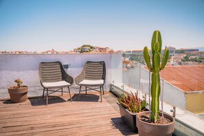 A rooftop terrace with two wicker chairs, a potted cactus, and a view of a cityscape. - Quinta Colina by Shiadu (Lisbon)