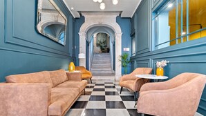Un vestíbulo de hotel con suelo de cuadros, una escalera y zonas de estar.