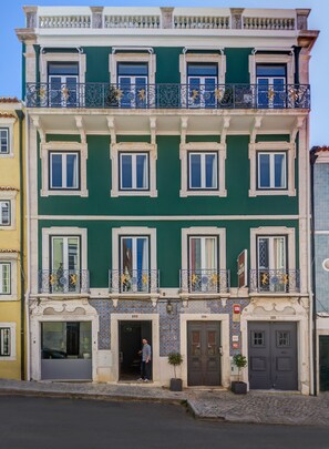 A multi-story building with a green facade, multiple balconies with ornate railings, and numbered doors. - Quinta Colina by Shiadu (Lisbon)