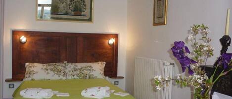 A neatly made bed with floral bedding, a wooden headboard, and bedside lamps.