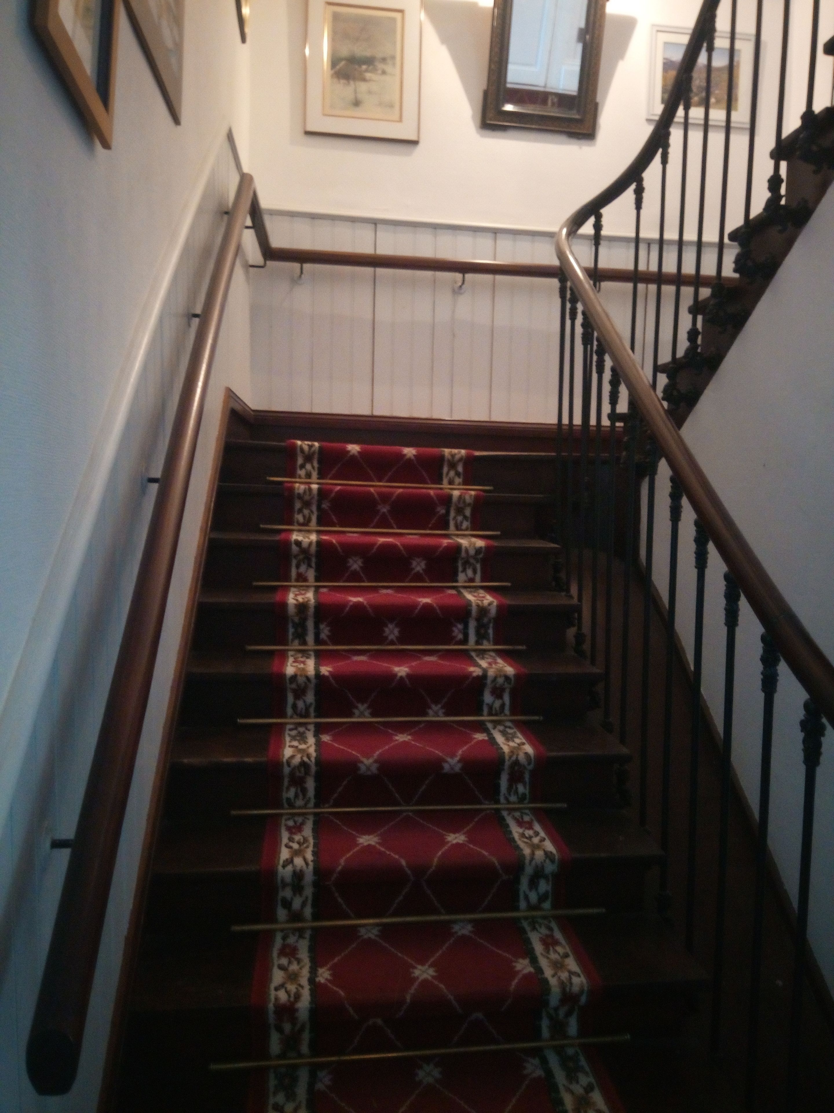 A staircase with red carpeted steps and wooden handrails.