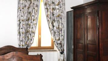 Una habitación con una cama de madera, un armario y una ventana con cortinas florales.