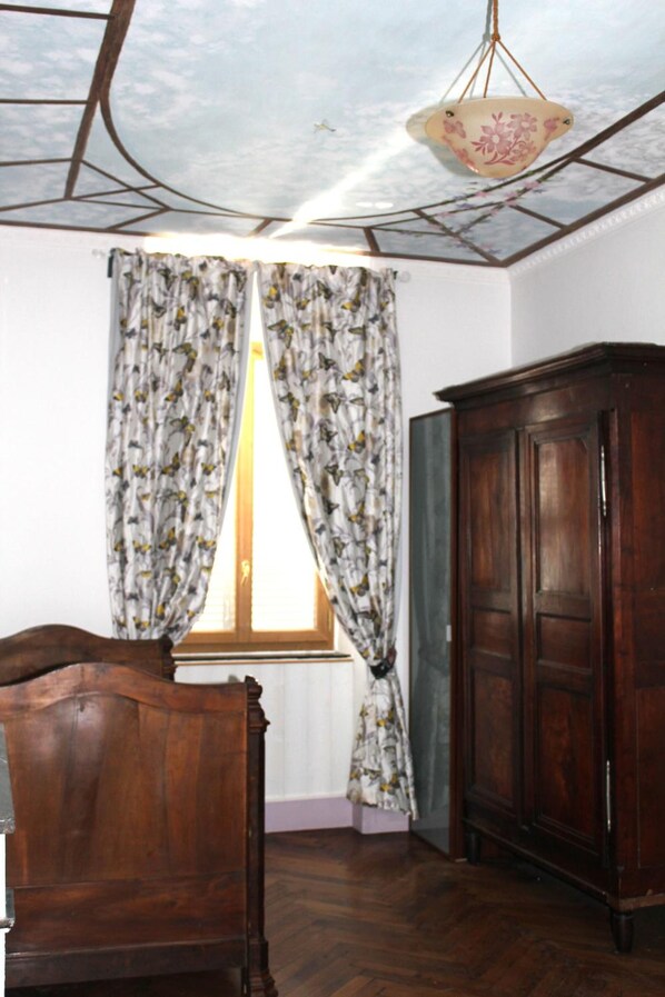 Una habitación con una cama de madera, un armario y una ventana con cortinas florales.