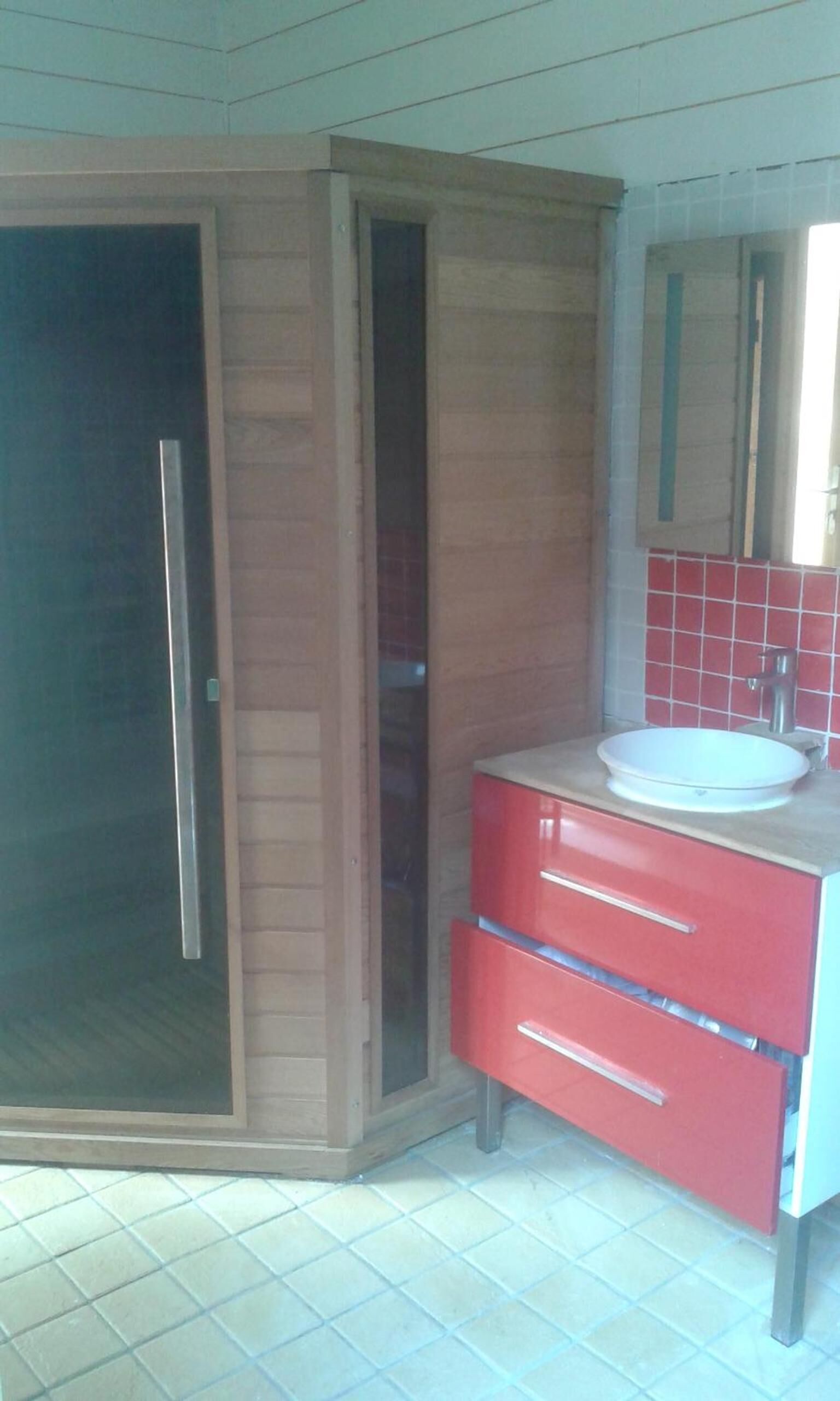 Un baño con puerta corredera, un lavabo con espejo y armarios rojos.