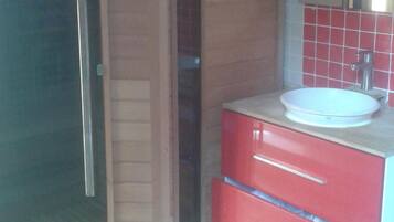 Un baño con puerta corredera, un lavabo con espejo y armarios rojos.