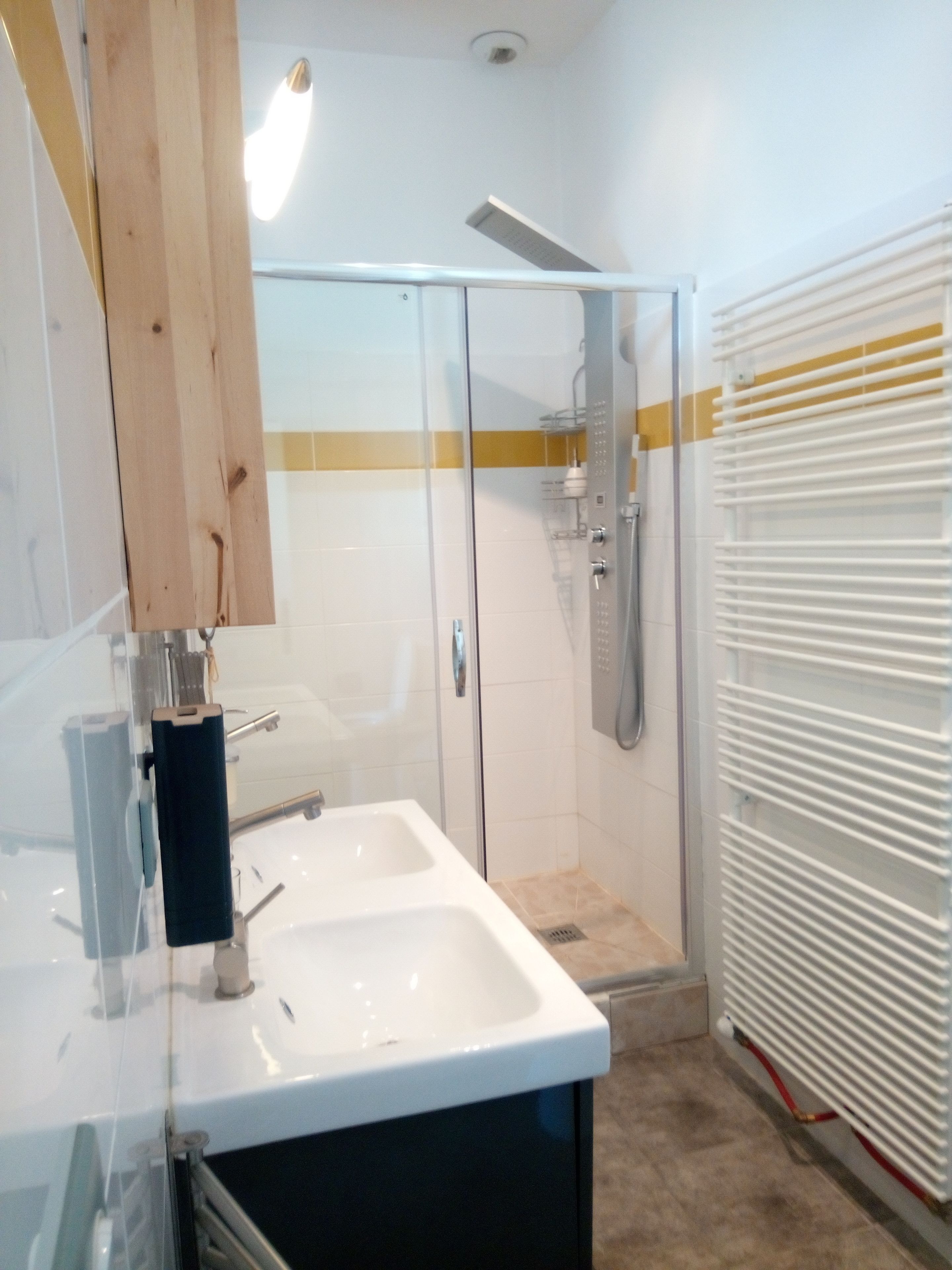 Un baño con cabina de ducha de vidrio, un lavamanos blanco y un perchero para toallas.