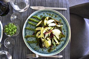 Un plato de comida con espárragos y lonchas de manzana sobre un plato azul.