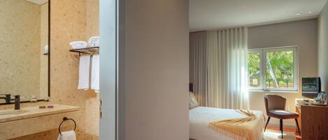 Ein modernes Hotelzimmer mit Bad, Bett, Schreibtisch und Blick ins Freie.