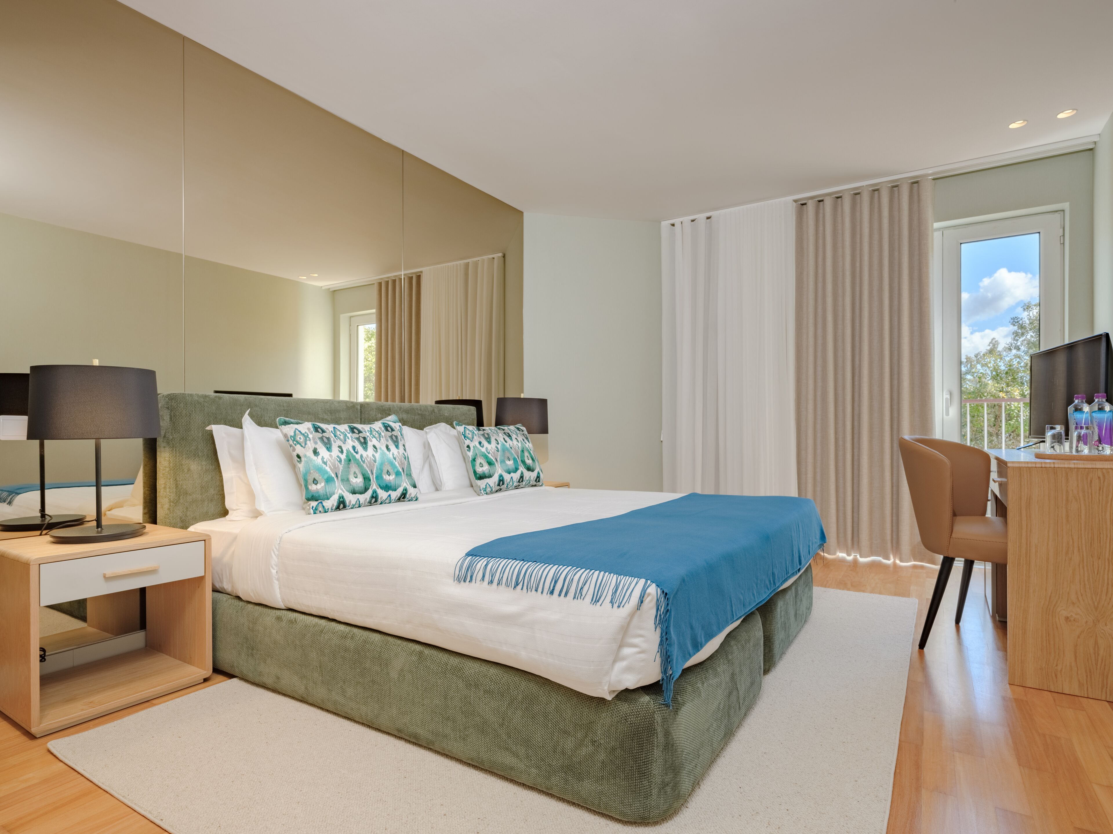 Habitación de hotel moderna con una cama grande, un escritorio y vistas al exterior.