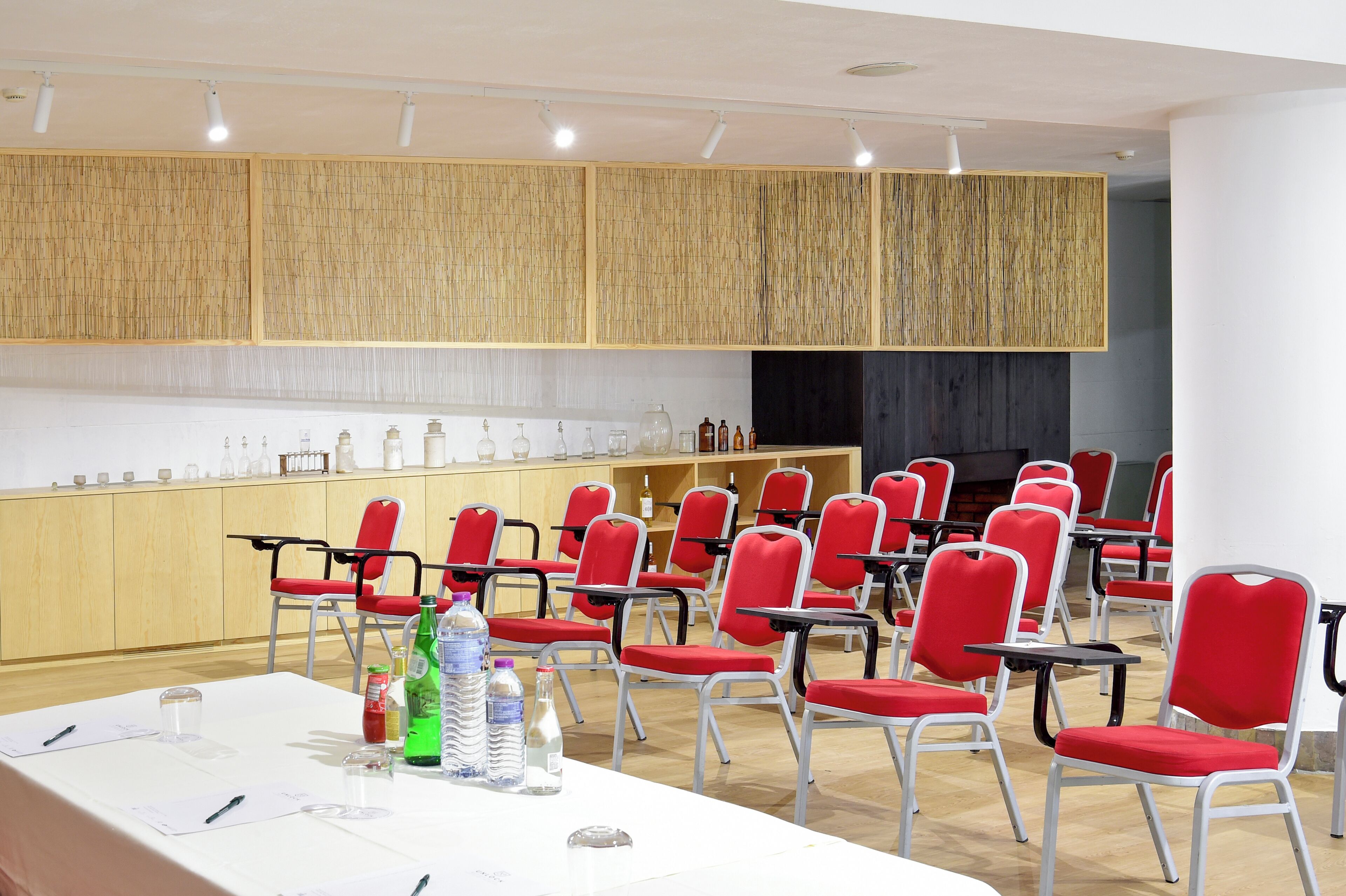 Una sala de conferencias con una larga mesa, sillas rojas y un panel de pared de madera.